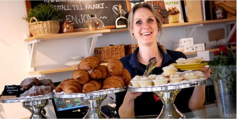 Barista holding a tray of cakes in cafe