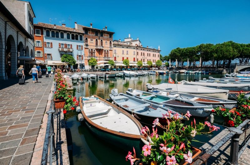 Boats on marina with tourists at cafes and restaurants at Desenzano del Garda, Lake Garda, Lombardy, Italian Lakes, Italy