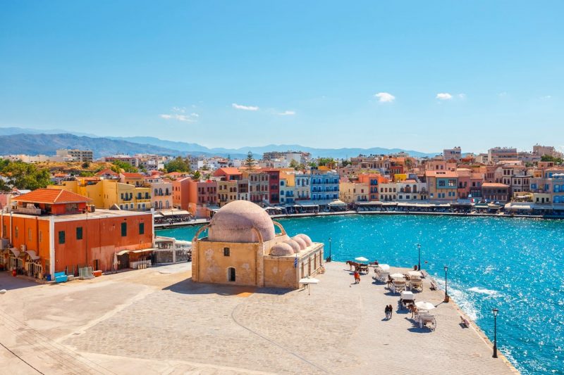 A view over buildings and bright turquoise water in Chania, Crete