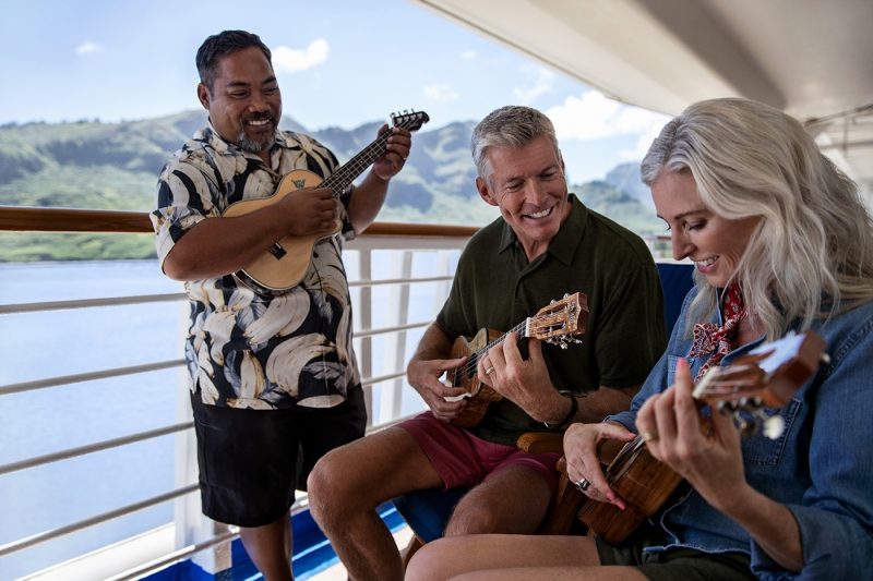 Couple playing ukelele onboard ship with instructor