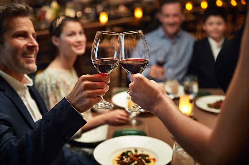 A group of people toasting with wine and pasta