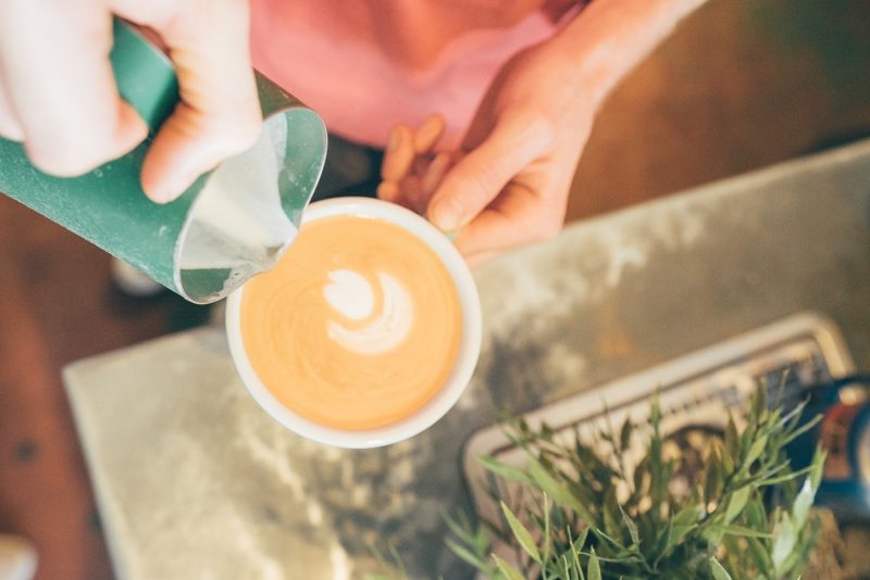 Person pouring milk into coffee cup