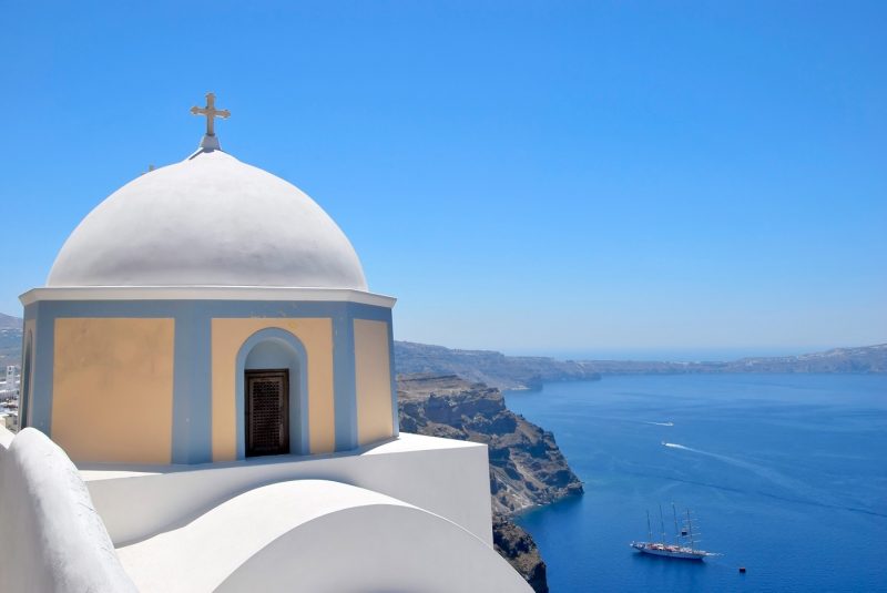 A traditional white domed church and blue sea in Santorini