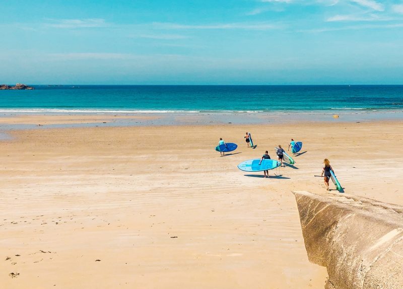 Group of people with surfboards running towards the sea