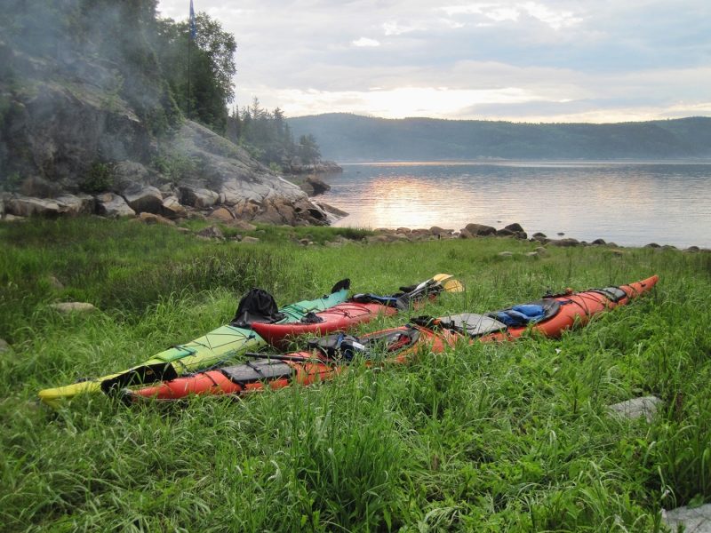 Two kayaks on grass by the sea in Saguenay, Canada