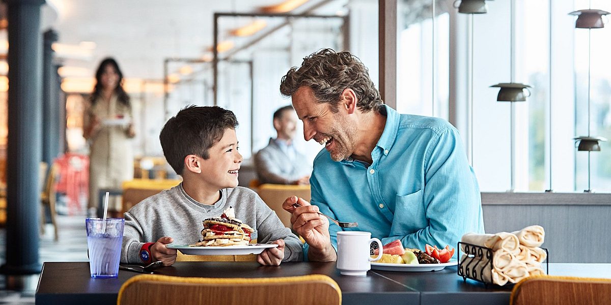 Father and son sat in World Fresh Marketplace, Princess Cruises