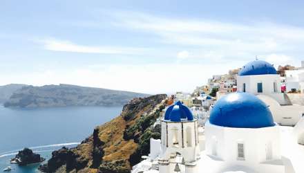 A view over Santorini featuring blue domes, cliffs and the sea